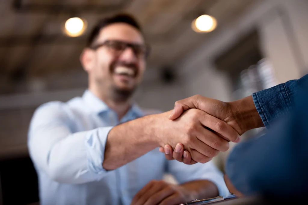 Handshake. Mann lacht.